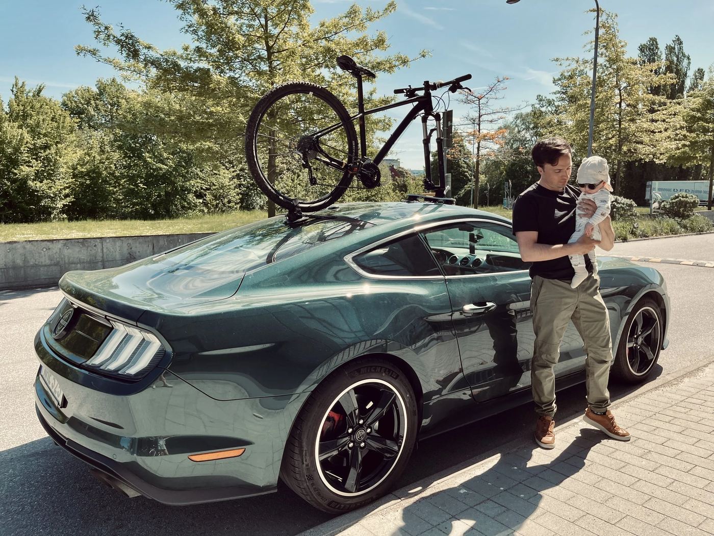 Timothy holding his son next to the Mustang with a bike mounted on the SeaSucker rack