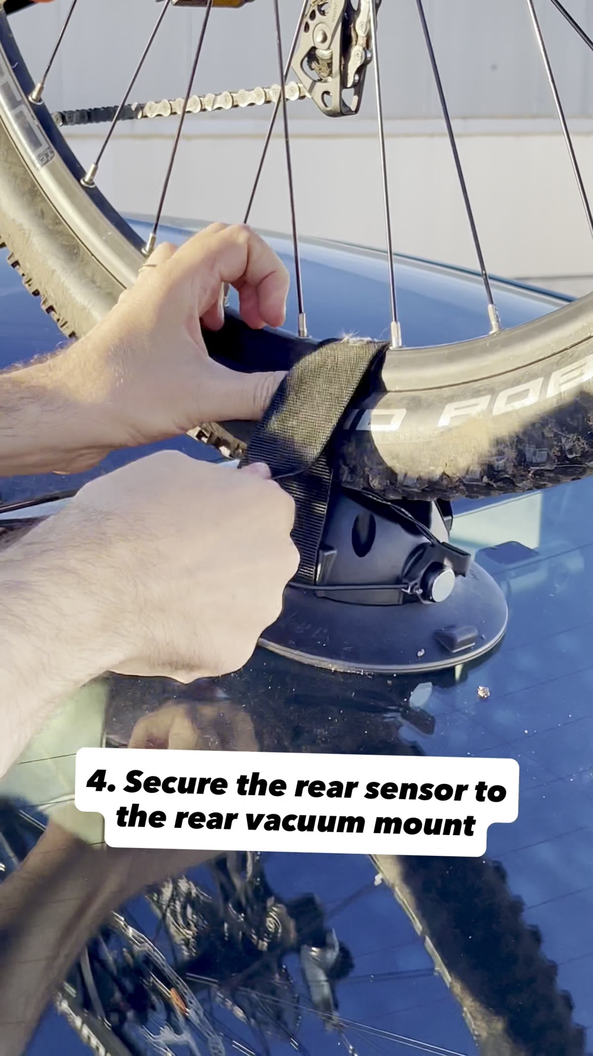A hand securing the rear sensor to the rear vacuum mount with an elastic strap